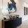a table with a lamp with art on the wall above it 